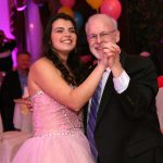 An older man dancing with a young girl at a party.