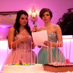 Two women standing in front of a cake.
