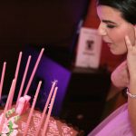 A girl in a pink dress blowing out candles on a cake.