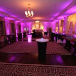 A large room with purple lighting and tables.