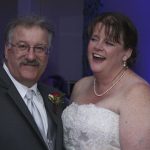 A man and woman smiling at each other at a wedding reception.