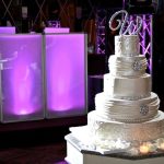 A wedding cake is sitting on a table in front of a purple light.