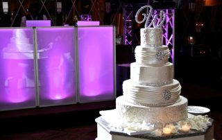 A wedding cake is sitting on a table in front of a purple light.