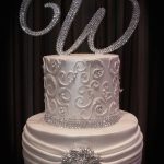 A white wedding cake decorated with rhinestones and crystals.