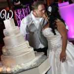 A couple kissing in front of a wedding cake.