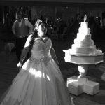 A woman in a wedding dress standing in front of a cake.