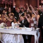 A wedding party with their hands raised in the air.