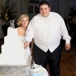 A man and a woman cutting a wedding cake.