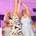 Two bridesmaids throwing bouquets into the air at a wedding.