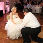 A bride and groom kneeling on the floor at a wedding reception.