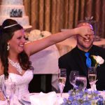 A bride and groom toasting at a table.