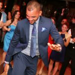 A man in a suit dancing at a wedding reception.
