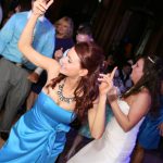A woman in a blue dress dancing at a wedding.
