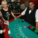 A group of people posing in front of a blackjack table.