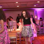 A girl in a pink dress dancing at a party.