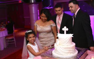 A little girl cutting a cake with her family.