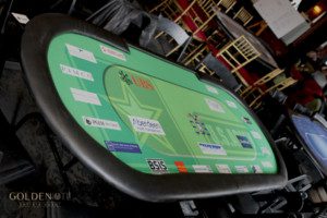 A green poker table in a room full of people.