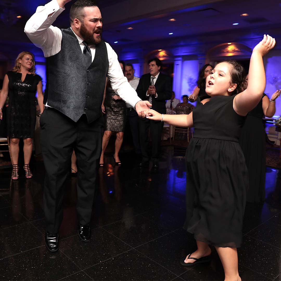 A man and a little girl dancing at a wedding reception.