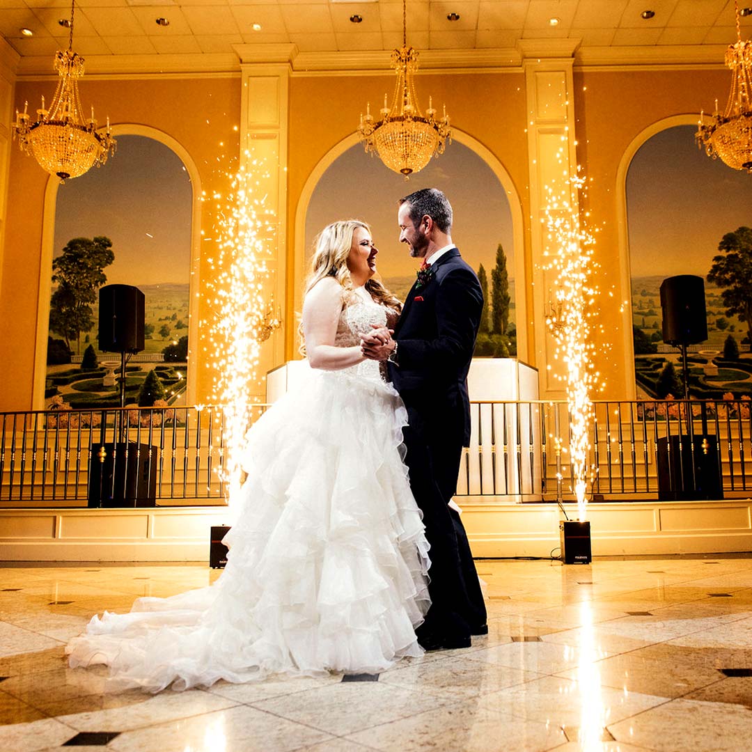 A wedding couple standing in front of a chandelier with sparklers.