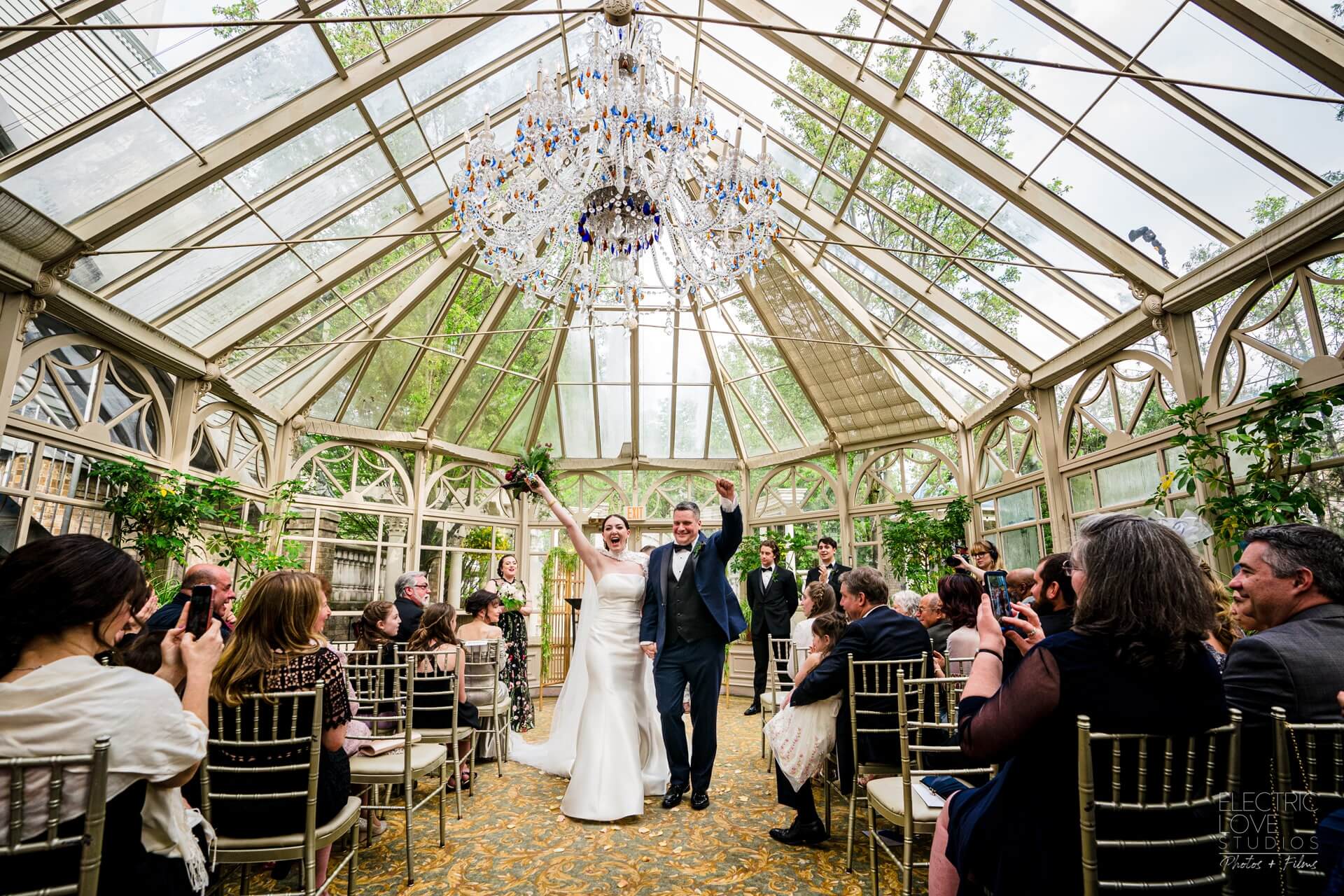 Bride and groom exit glass ceremony space.