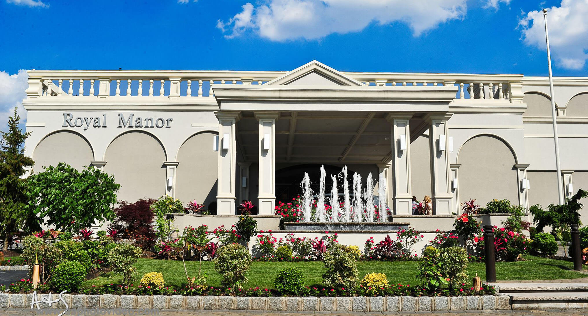 Royal Manor building with fountain and flowers.